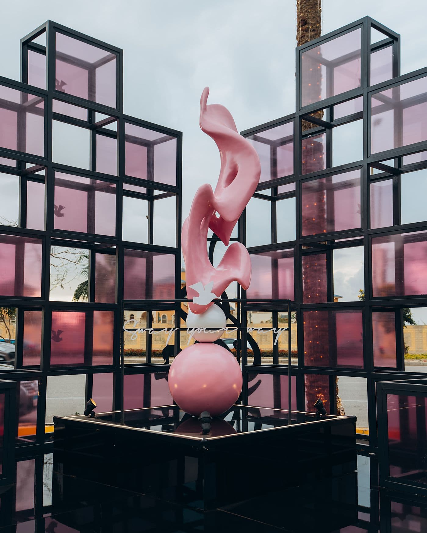 Pink calligraphy sculpture inside a black steel cube installation