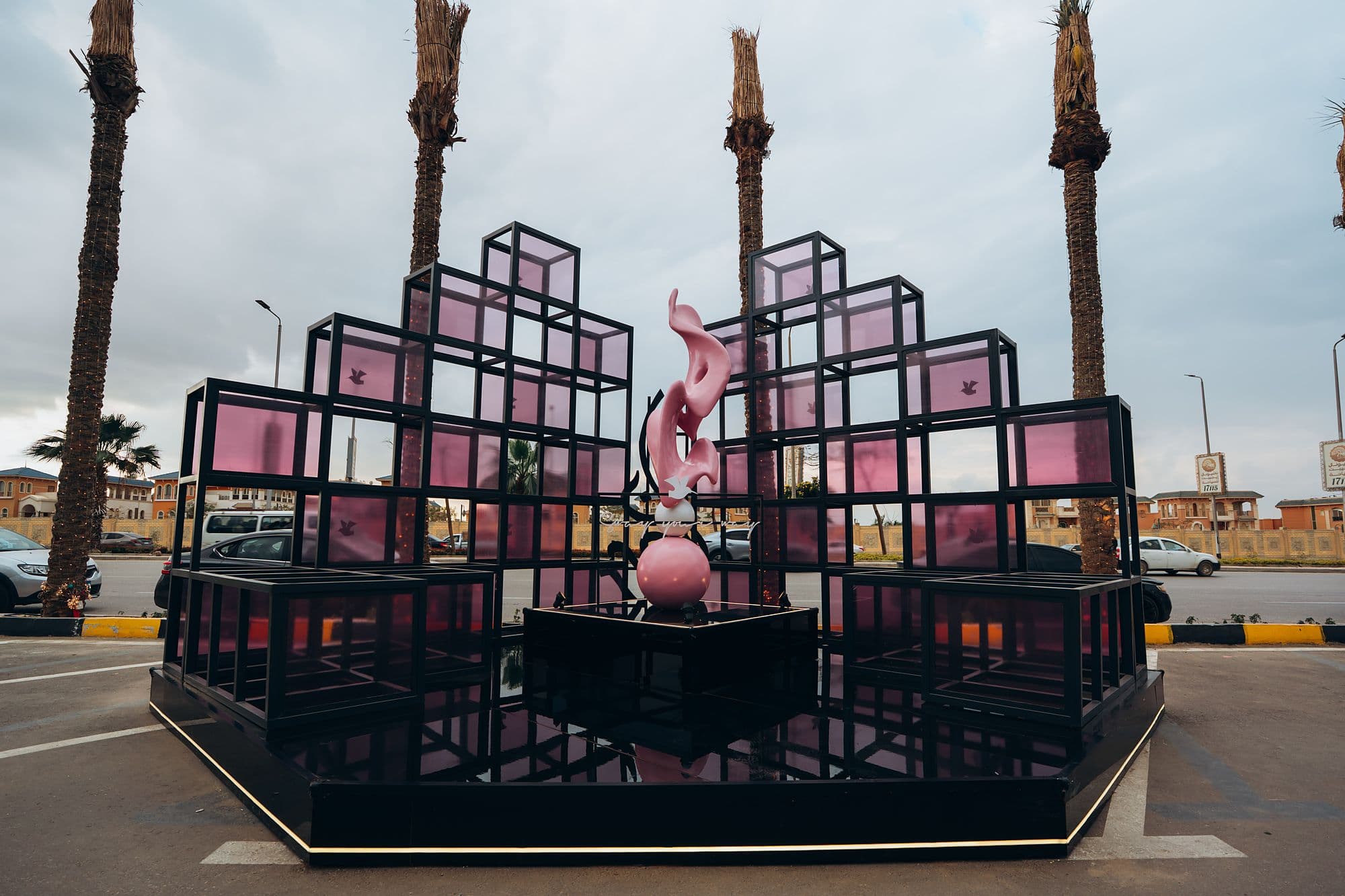 Front view of the black steel cube installation with pink sculptures