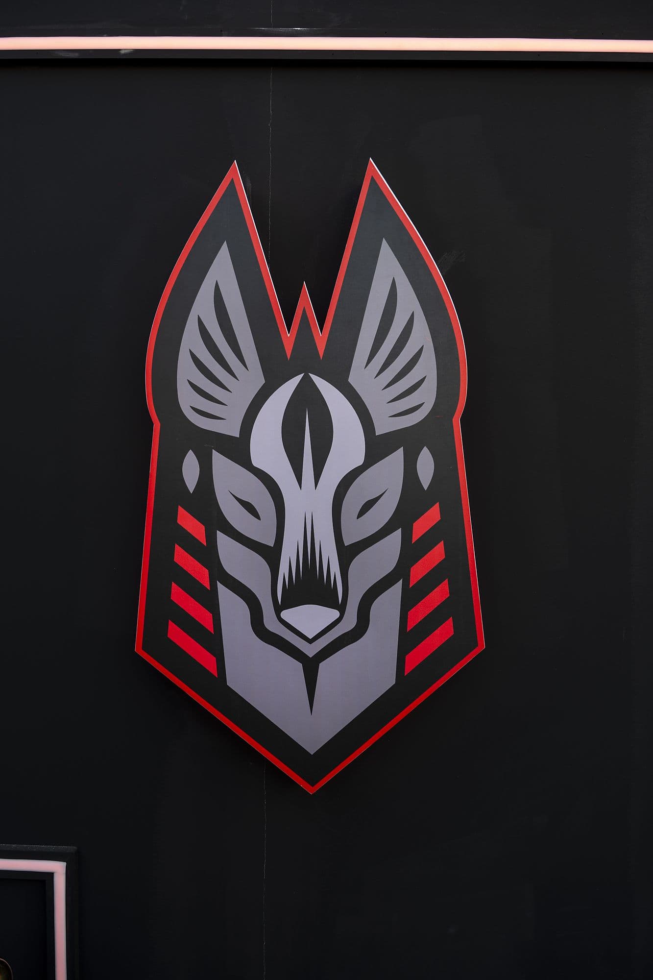 Illuminated Anubis crest in grey and red on a black wall